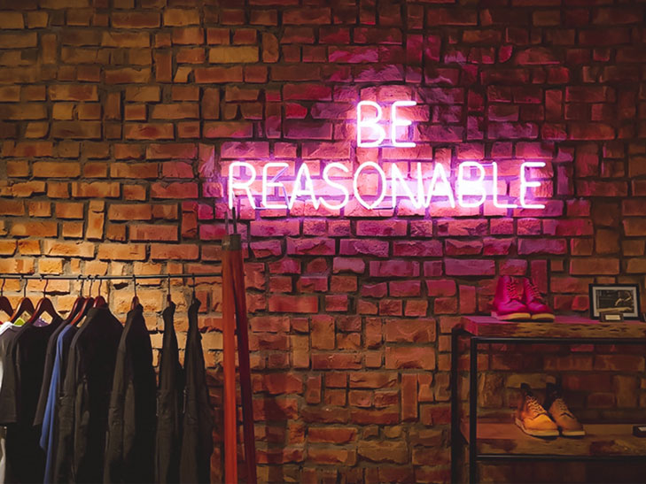 Ein neonfarbener Schriftzug mit den Worten “Be Reasonable” ist auf einer Backsteinwand angebracht. Der verantwortungsvolle Umgang mit dem Vereinsvermögen ist der erste und wichtigste Grundsatz, wenn Sie es in Aktien anlegen möchten.