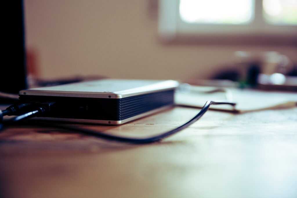 Eine externe Festplatte liegt auf einem Schreibtisch. Ihre Vereinsunterlagen sollten Sie regelmäßig auf einem physischen Speichermedium sichern.